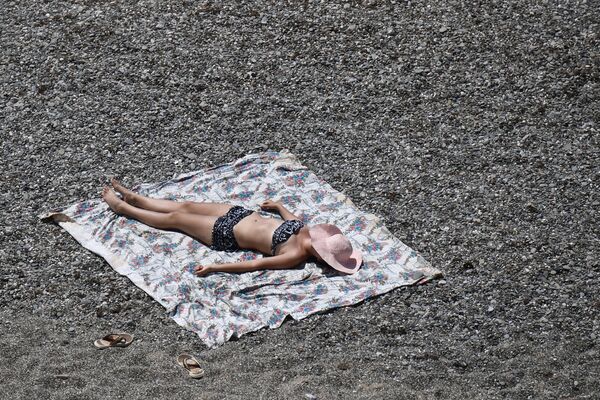 Девушка загорает на пляже возле мыса Меганом в Крыму