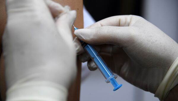 Медик делает прививку с вакциной против гриппа