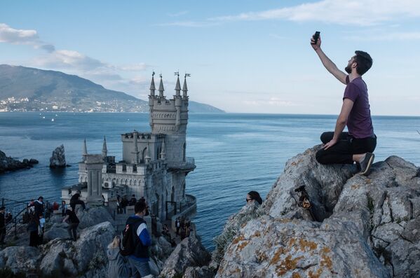 Туристы на береговой скале рядом с замком Ласточкино гнездо в поселке Гаспра в Крыму.