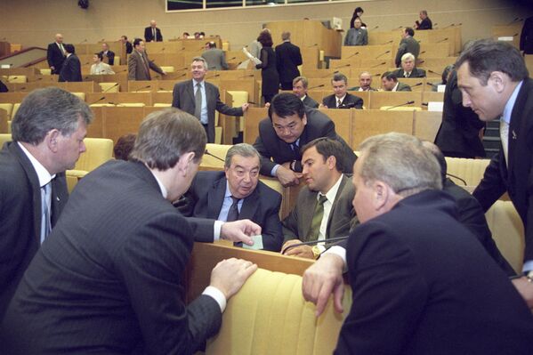 Депутат Евгений Примаков (на среднем плане слева) среди коллег в зале заседаний Государственной Думы Российской Федерации.