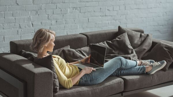 Молодая девушка с ноутбуком на диване