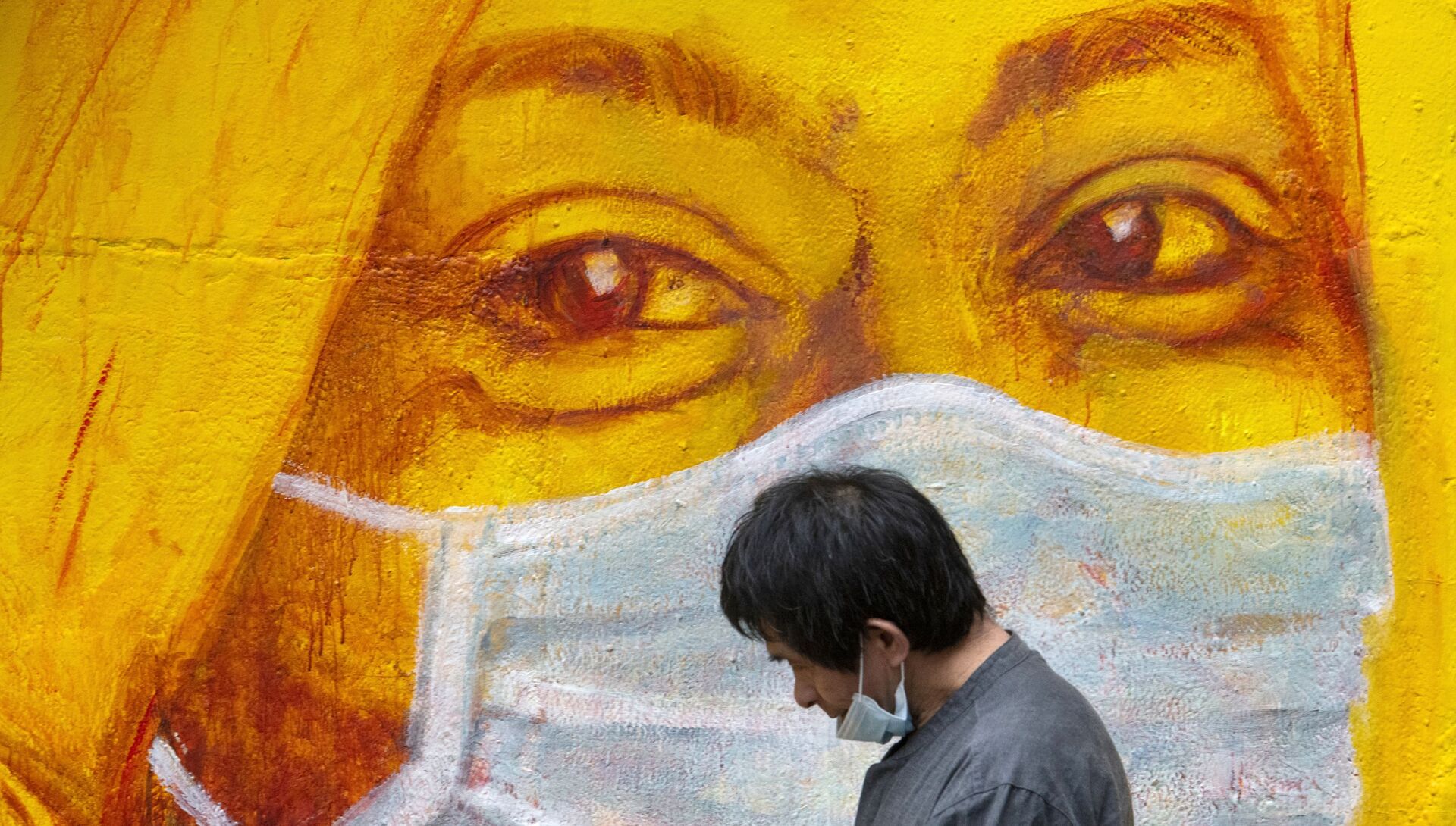 Прохожий около стены с изображением человека в маске в Гонконге - РИА Новости, 1920, 15.04.2021