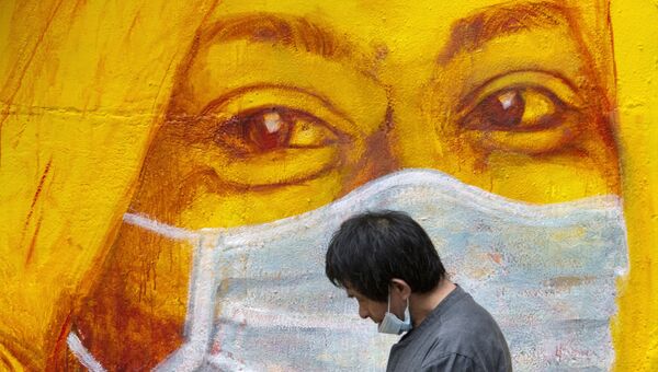 Прохожий около стены с изображением человека в маске в Гонконге