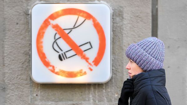 Женщина около таблички курение запрещено в Москве