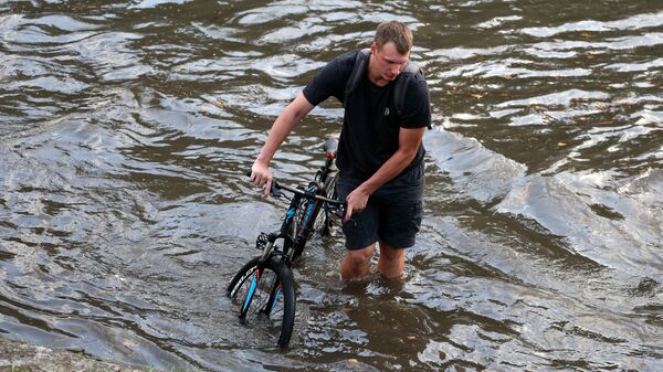 Велосипедист на подтопленной после мощного ливня улице