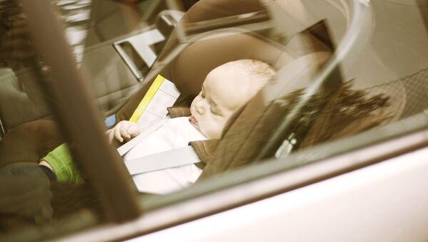 Cпящий ребенок в автомобильном кресле в машине