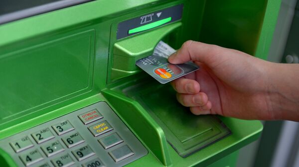 Мужчина засовывает в банкомат банковскую карту. Архивное фото